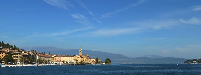 Trip Albanien beliebte Urlaubsziele am Gardasee -  Mit einer Fläche von 370 km² ist der Gardasee der größte See Italiens. Es liegt am Fuße der Alpen und erstreckt sich über drei Staaten: Lombardei, Venetien und Trentino. Die maximale Tiefe des Sees beträgt 346 m, er hat eine längliche Form und sein nördliches Ende ist sehr schmal. Dort ist der See von den Bergen der Gruppo di Baldo umgeben. Du trittst aus deinem gemütlichen Hotelzimmer und es begrüßt dich die warme italienische Sonne. Du blickst auf den atemberaubenden Gardasee, der in zahlreichen Blautönen schimmert - von tiefem Dunkelblau bis zu funkelndem Türkis. Majestätische Berge umgeben dich, während die Brise sanft deine Haut streichelt und der Duft von blühenden Zitronenbäumen deine Nase kitzelt. Du schlenderst die malerischen, engen Gassen entlang, vorbei an farbenfrohen, blumengeschmückten Häusern. Vereinzelt unterbricht das fröhliche Lachen der Einheimischen die friedvolle Stille. Du fühlst dich wie in einem Traum, der nicht enden will. Jeder Schritt führt dich zu neuen Entdeckungen und Abenteuern. Du probierst die köstliche italienische Küche mit ihren frischen Zutaten und verführerischen Aromen. Die Sonne geht langsam unter und taucht den Himmel in ein leuchtendes Orange-rot - ein spektakulärer Anblick.
